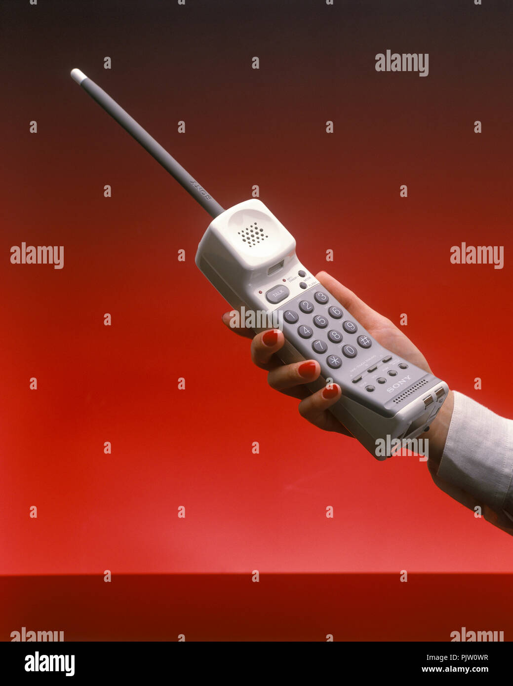1991 historische WOMANS HAND BIS SCHNURLOSES TELEFON (© SONY CORP 1990) auf  rotem Hintergrund Stockfotografie - Alamy