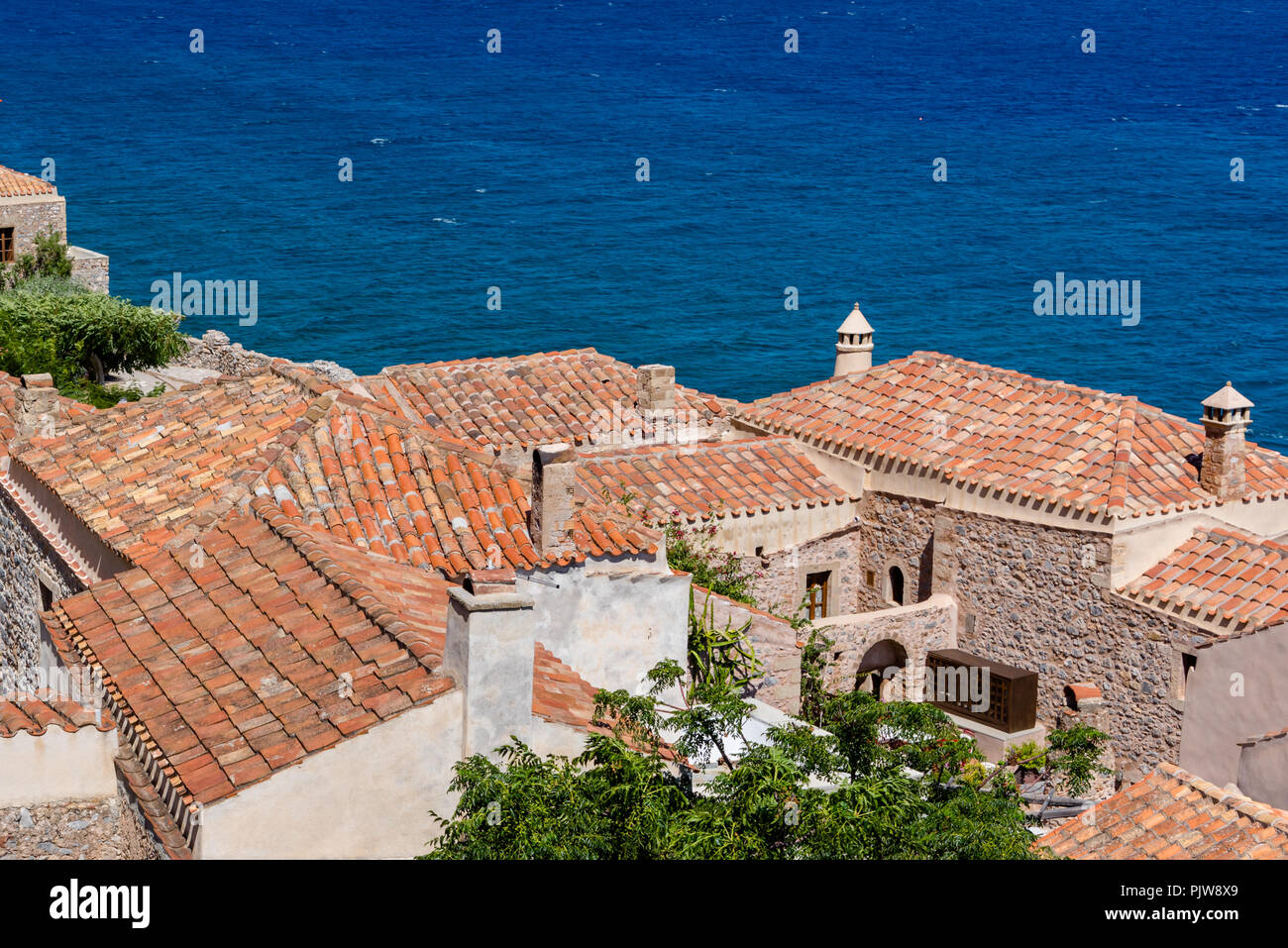 Traditionelle Dorf an der Küste auf der griechischen Insel mit rotem Schiefer Dächer, Schornsteine und Adobe Wände Stockfoto