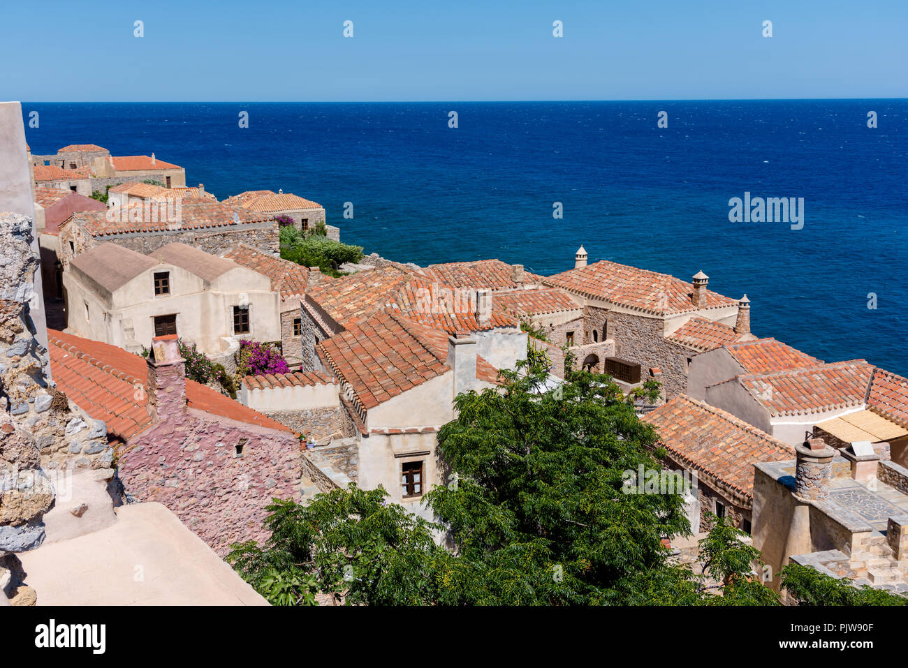 Traditionelle Dorf an der Küste auf der griechischen Insel mit rotem Schiefer Dächer, Schornsteine und Adobe Wände Stockfoto