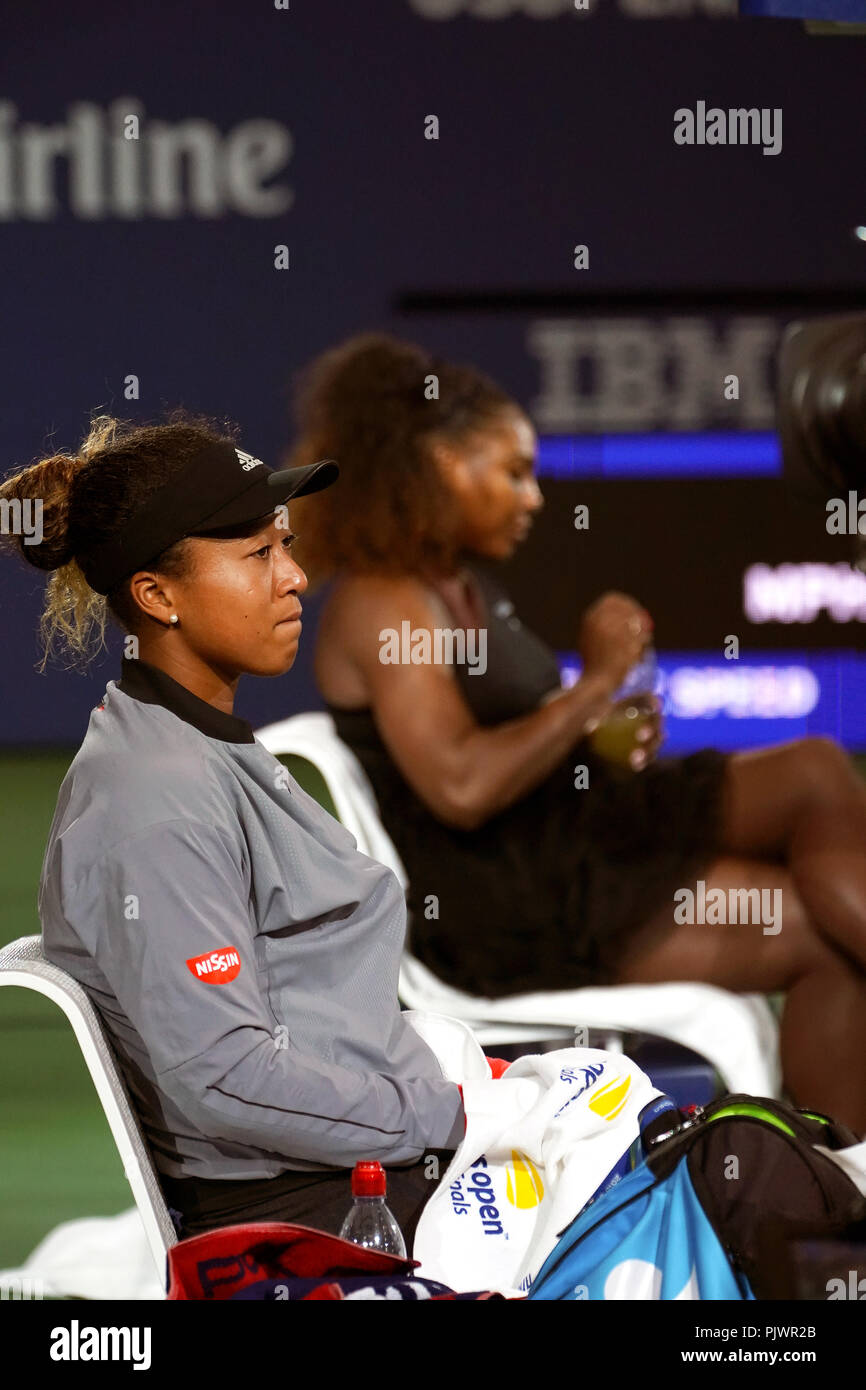 New York, USA. 8. September 2018. US Open Tennis: Naomi Osaka in Japan, in den Vordergrund, sitzt still nach dem Sieg über Serena Williams, im Hintergrund, in der die US Open für Frauen endgültig. Williams war ein Spiel bei 4-3 im abschließenden Satz, die Kontroverse, die für die match hinzugefügt bestraft. Quelle: Adam Stoltman/Alamy Leben Nachrichten Quelle: Adam Stoltman/Alamy Leben Nachrichten Quelle: Adam Stoltman/Alamy leben Nachrichten Stockfoto