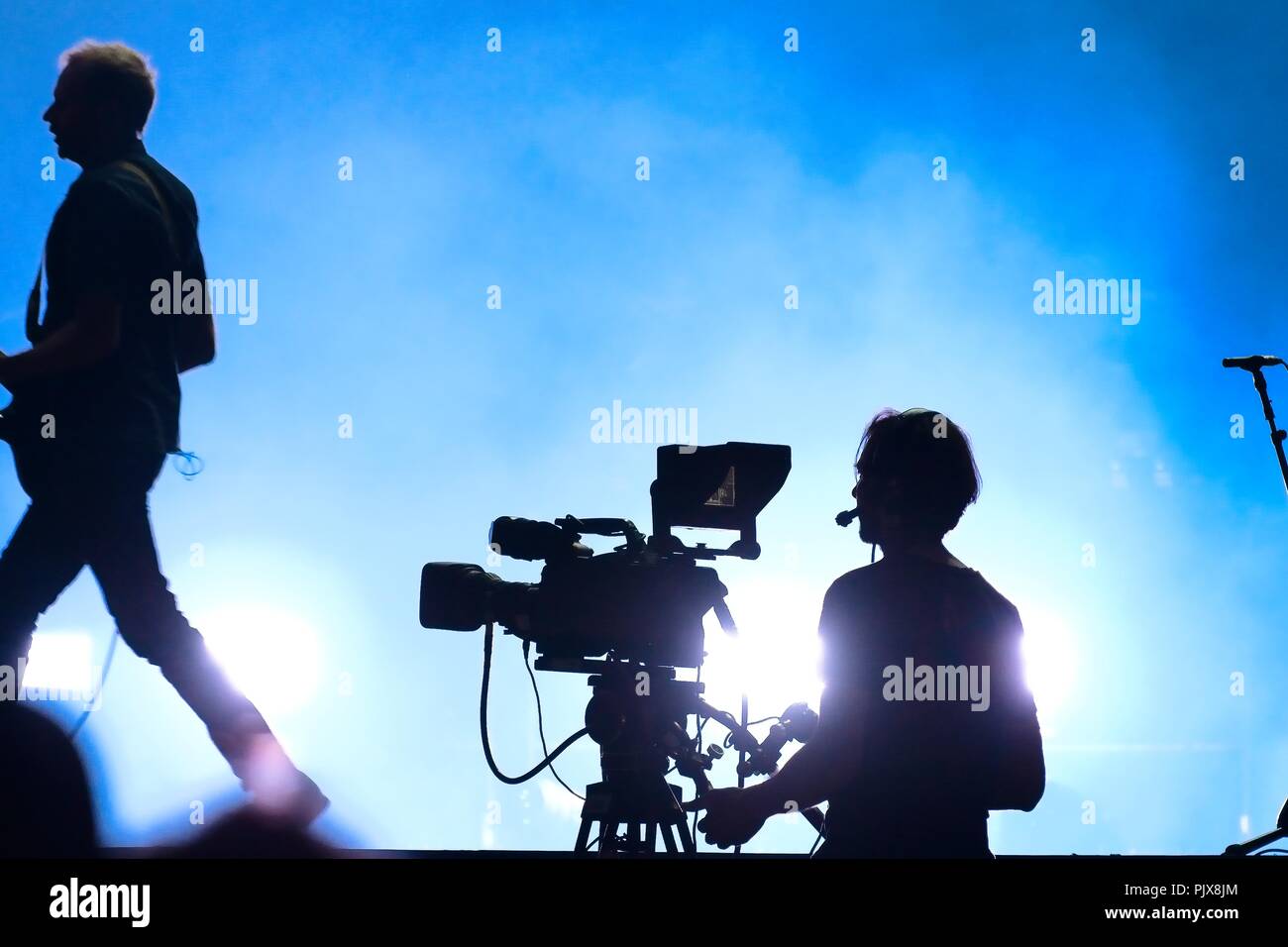 Silhouette der Kameramann und ein Gitarrist in einem Konzert. Blau Atmosphäre. Live Konzert Stockfoto
