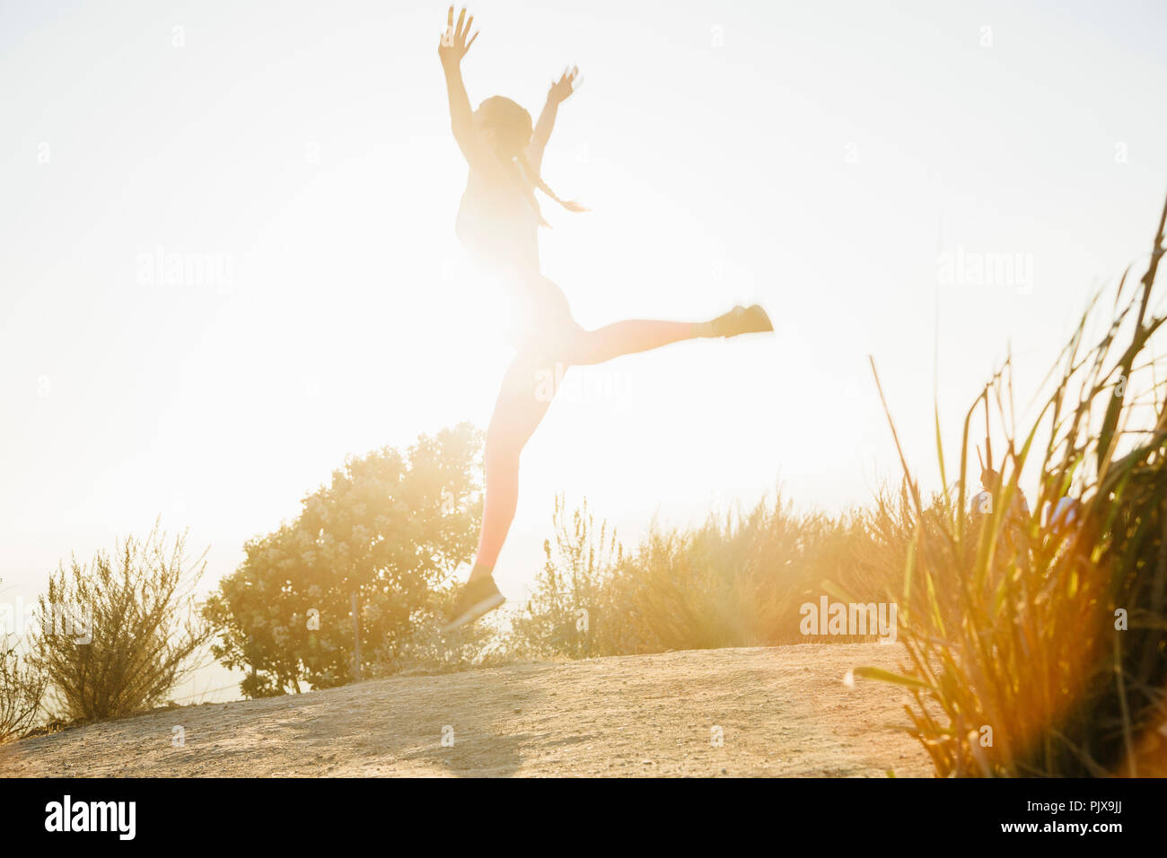 Frau springen in die Luft auf dem Hügel Stockfoto