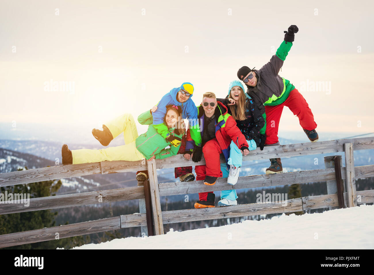 Gruppe von Happy friends ist Spaß an der Skistation gegen Sonnenuntergang in den Bergen Stockfoto