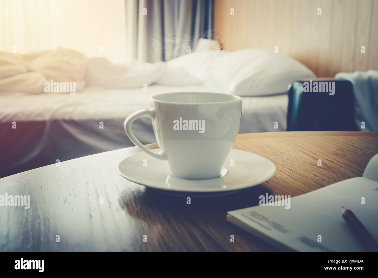 Kaffeetasse auf hölzernen Tisch Morgen Kaffee im Bett Zimmer zum Aufwachen leben - Warme vintage Tone Stockfoto