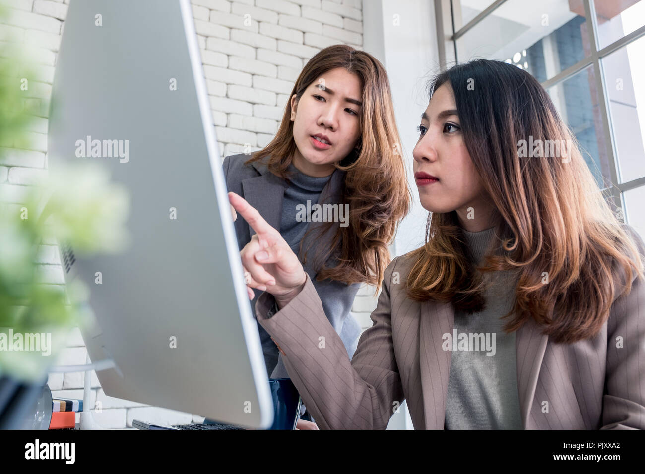 Zwei Kollegen Geschäftsfrau Diskussion über Arbeit verwenden Desktop Computer im Fenster in modernen Büro. Digital Business Lifestyle Konzept Stockfoto