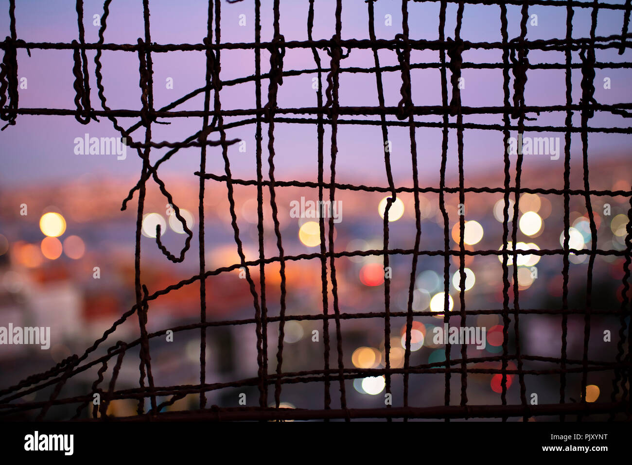 Unscharf, in der Nähe von Valparaiso in der Dämmerung durch einen Zaun. Urban abstrakt, Blick auf die Stadt mit bokeh Lichter, drahtzaun Muster. Valparaiso, Chile Stockfoto