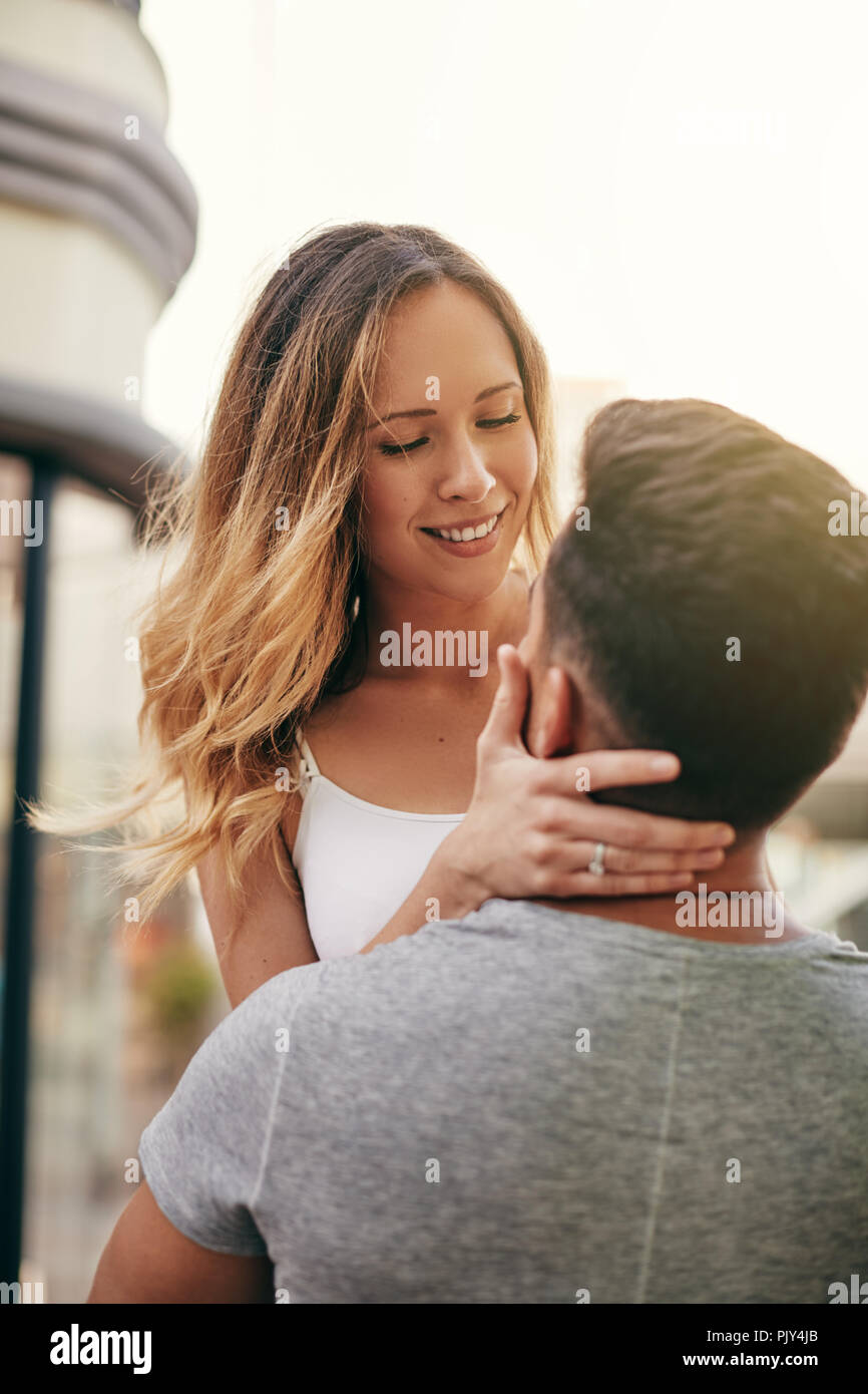 Lächelnde junge Frau in der Luft von ihrem Freund gehalten werden, während eine romantischen Moment gemeinsam die Stadt Stockfoto