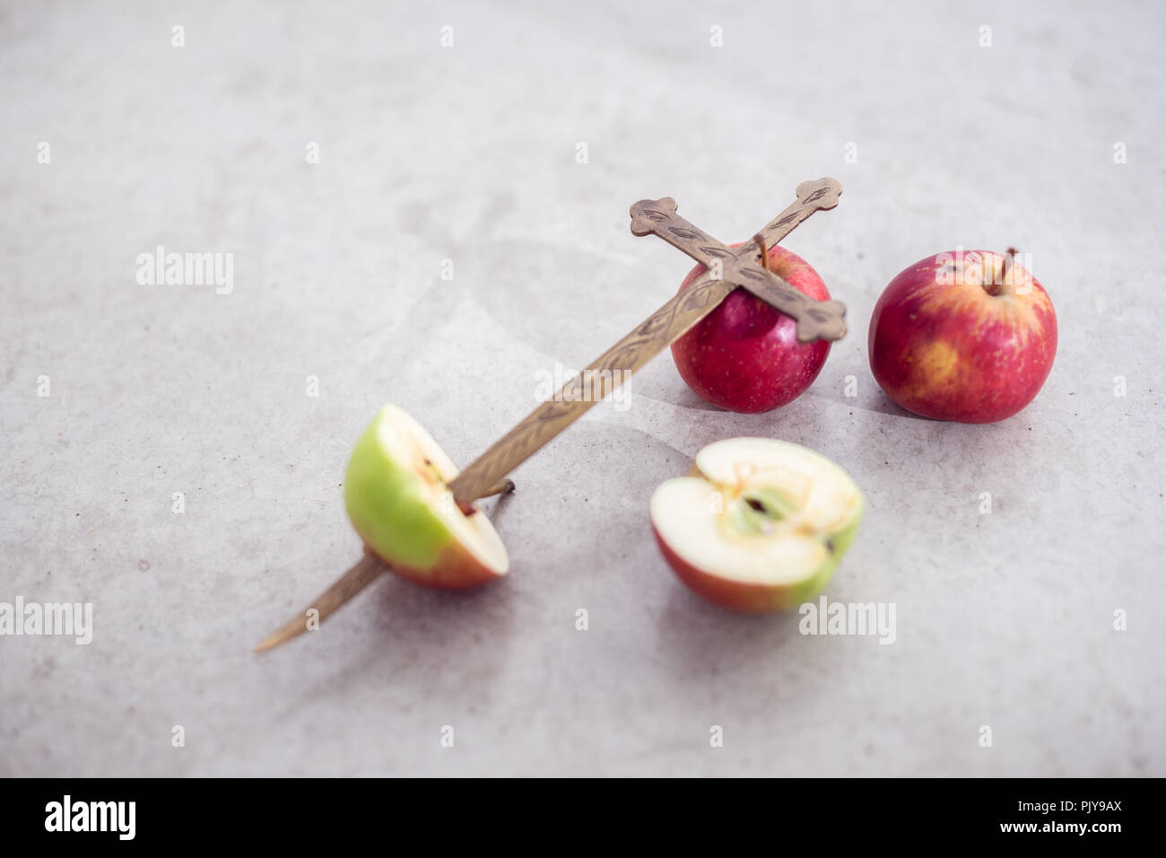 Noch immer leben konzeptionelle Szene eines eingerichteten Metall Kreuz mit ganzen und in Scheiben geschnittenen Äpfel, ein Apple durch das Metall Kreuz durchbohrt wurde Stockfoto