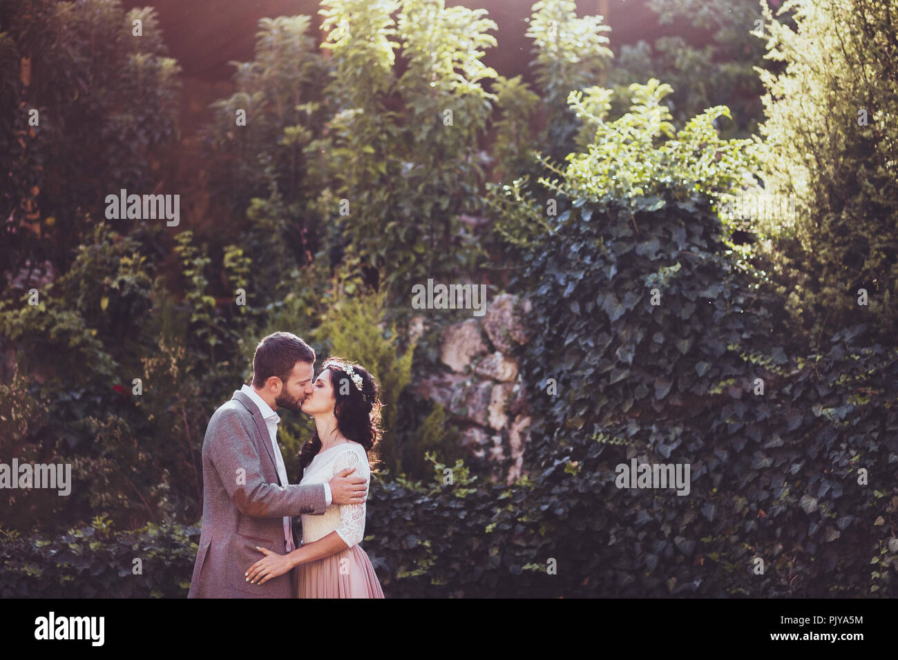 Bräutigam zärtlich küssen Braut durch die Natur in der Umgebung Stockfoto