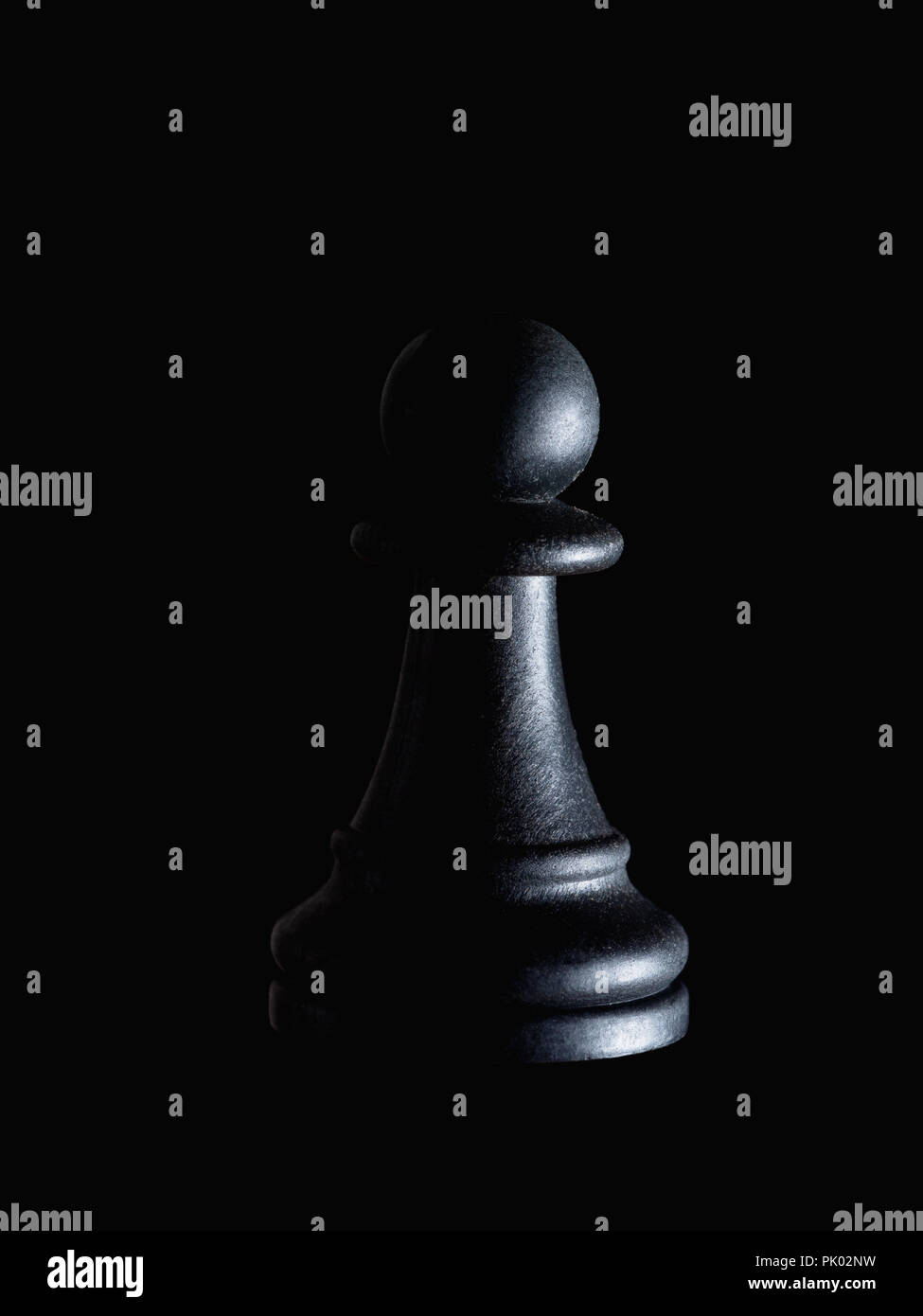 Einzelne schwarze Schachfigur Schachfigur auf Schwarz, dramatische Beleuchtung. Manipulation, Ohnmacht, versteckte Opfer Konzept. Stockfoto