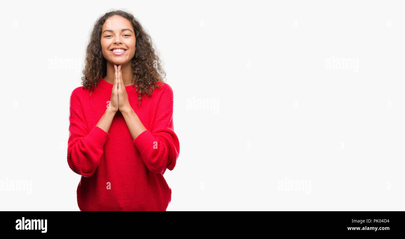 Junge Hispanic Frau das Tragen der roten Pullover mit Hände zusammen beten um Vergebung bat lächelnd zuversichtlich. Stockfoto