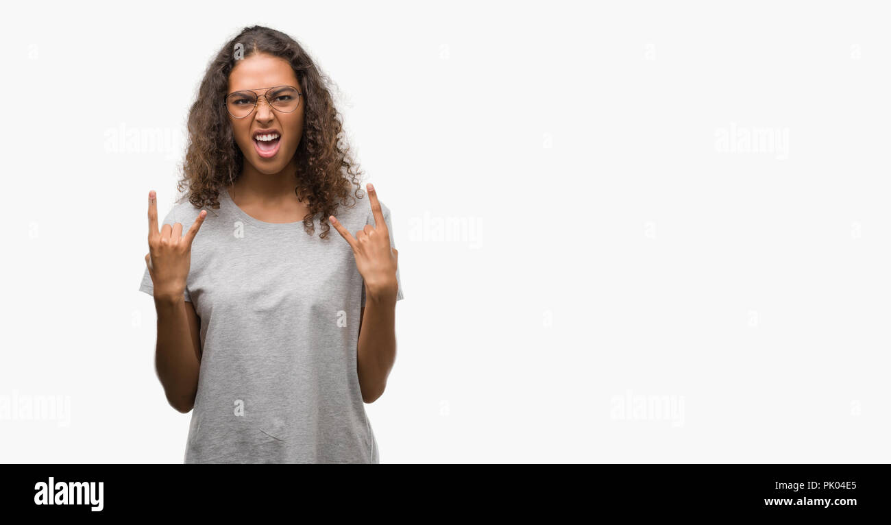 Schöne junge Hispanic Frau Brille schreien mit verrückten Ausdruck tun Rock Symbol mit hands up. Musik Star. Schwere Konzept. Stockfoto