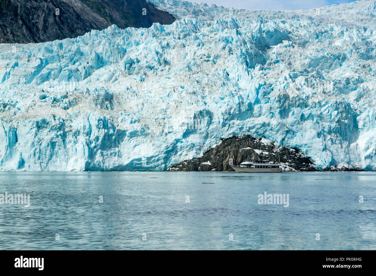 Harriman Aialik Gletscher, Bucht, Alaska, USA. Ein Katamaran wird durch die riesige blaue Eis Gletscher im Hintergrund in den Schatten gestellt. Stockfoto