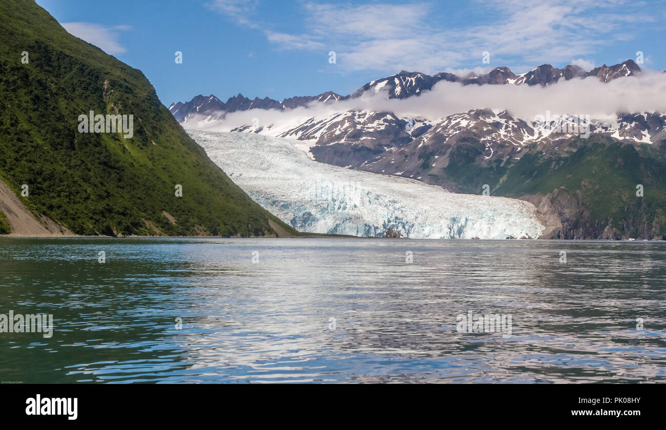 Ansicht der Aialik Gletscher in der Aialik Bay, Alaska, USA. Wasser im Vordergrund, Green mountain glacier Links, Schnee auf den Bergen auf der rechten, blauen Himmel. Stockfoto