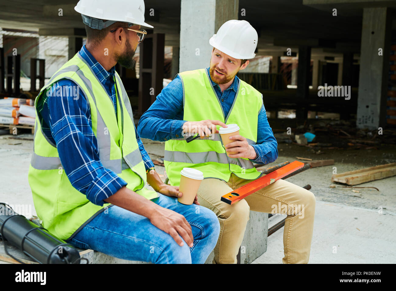 Verwirrt Arbeiter im Gespräch mit Kollegen über Bauvorhaben Stockfoto