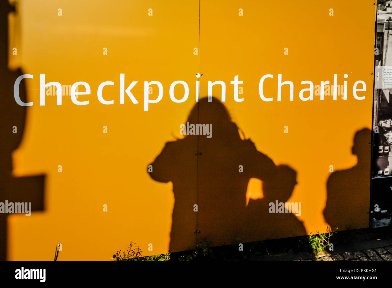 Schatten der Touristen spiegeln auf Plakatwänden am Checkpoint Charlie Museum in Berlin, Deutschland Stockfoto