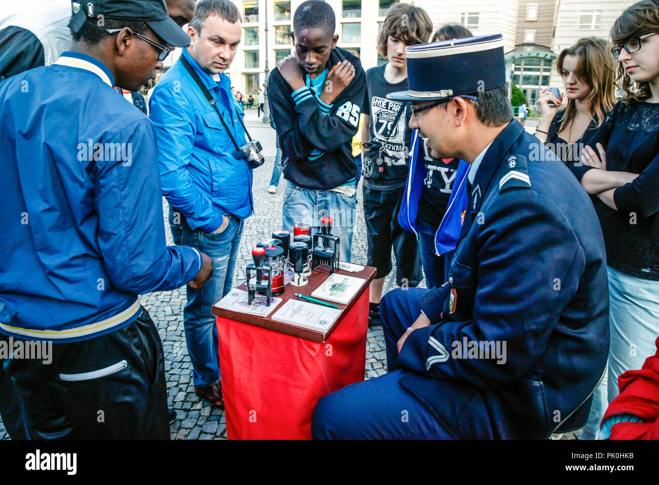 Mann verkleidet als französische Gendarmerie in der Nähe von Brandenburger Tor mit souvenir Kalten Krieges Pässe für Leute, die zu Besuch in Berlin sitzt, Deutschland Stockfoto