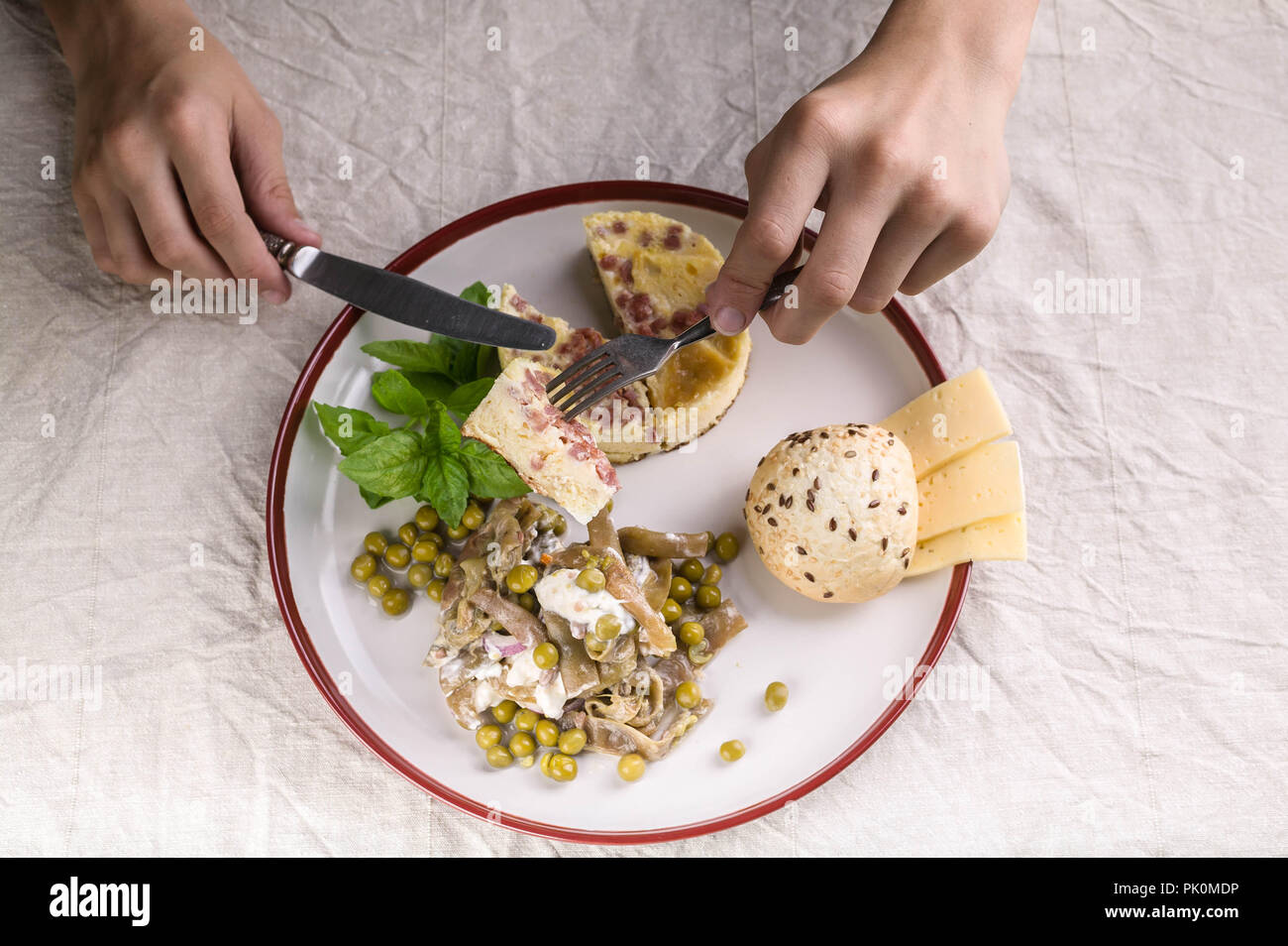 Gesundes und Leckeres Frühstück. Männliche Hände halten eine Gabel und Messer im Hintergrund einer Platte mit einem Omelette. Ansicht von oben Stockfoto