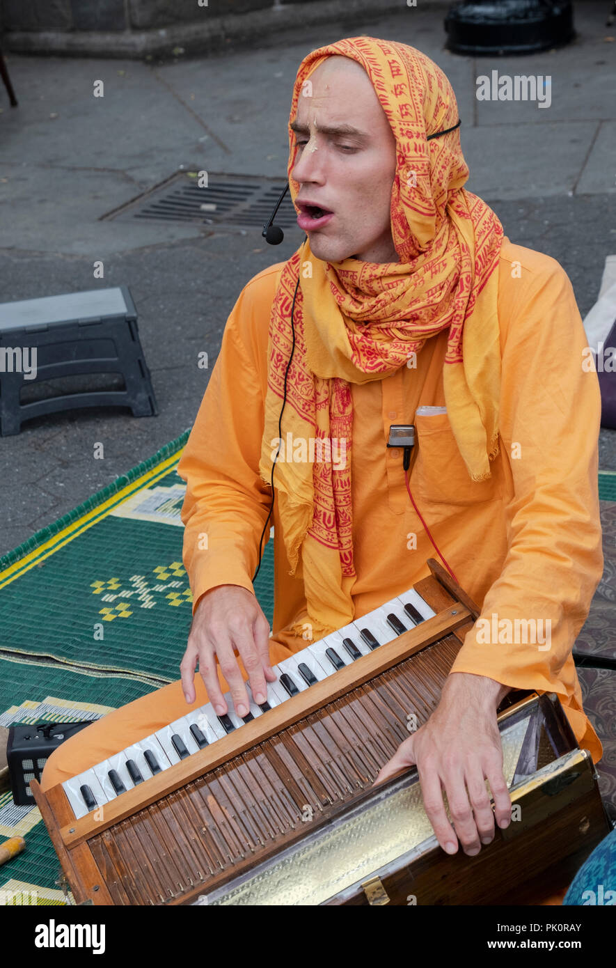 Ein Hase Krishna Anhänger das Harmonium spielen und singen in Union Square Park in Manhattan, New York City. Stockfoto