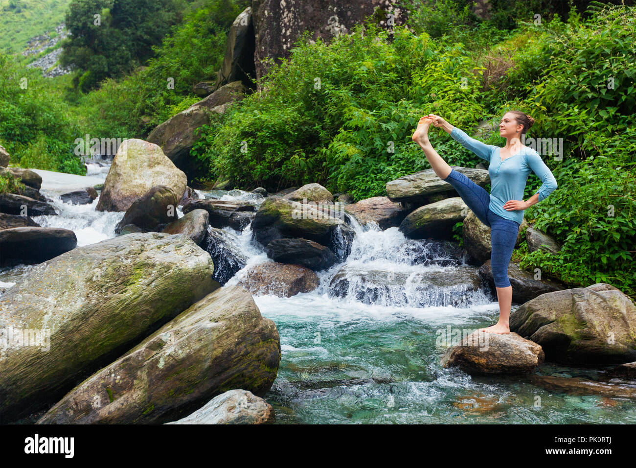 Frau tut Ashtanga Vinyasa Yoga Asana im Freien am Wasserfall Stockfoto