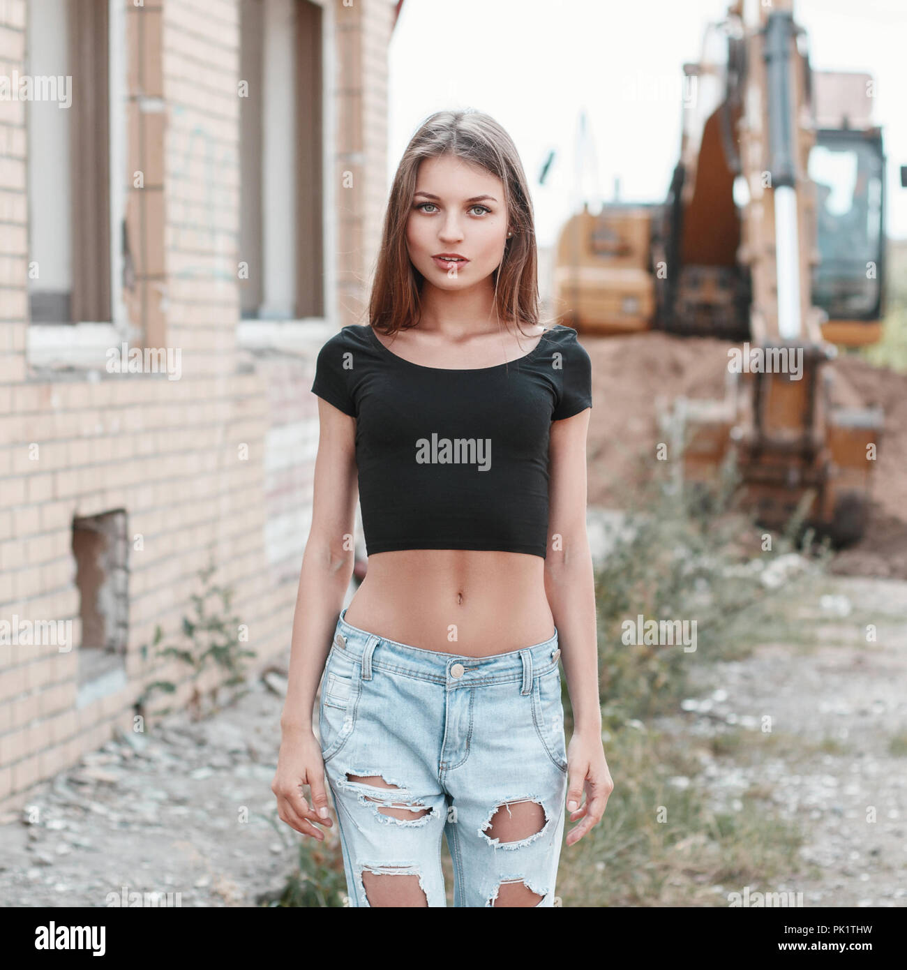 Schöne Mädchen in zerrissenen Jeans auf einer Baustelle in der Nähe des  Baggers Stockfotografie - Alamy