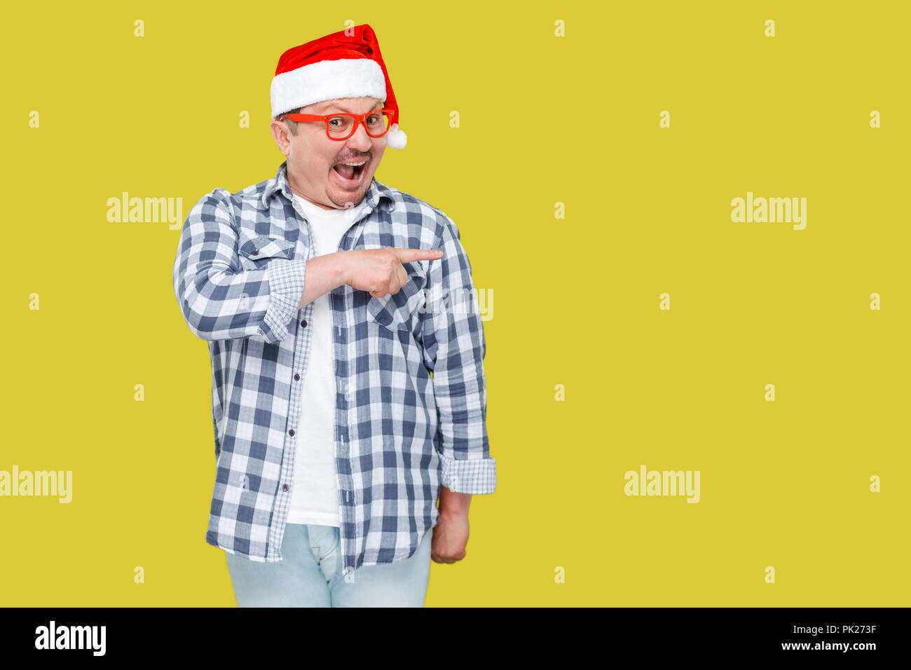 Positive im mittleren Alter Mann in Rot Neu Jahr santa Kappe und lässigen Stil, stehend, Zeigefinger auf leere Raum und mit überrascht Gesicht, Stockfoto