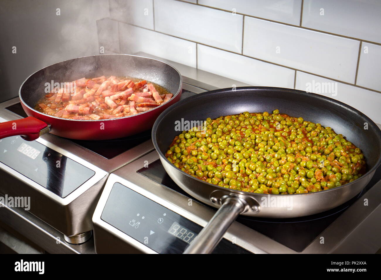 Niedrige Erbsen und Pancetta in Wanne auf elektrischer Ofen zubereitet Stockfoto