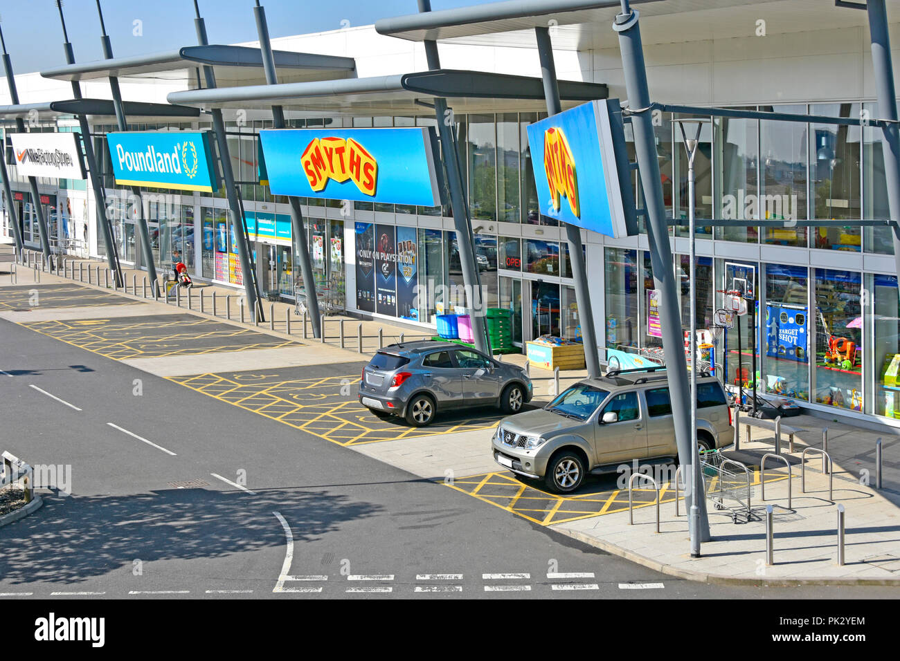 Auf Smyths Spielzeug & Poundland shopping Stores & Rollstuhlfahrer Behinderung Parkplatz Thurrock Shopping Park Essex England Großbritannien Stockfoto