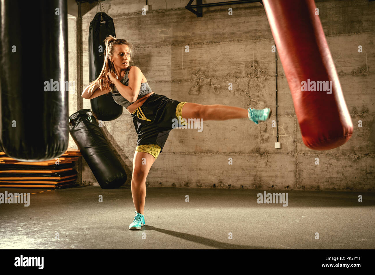Muskulöse Frau Stanzen mit Bein ein Boxsack auf Cross fit Training im Fitnessstudio. Stockfoto