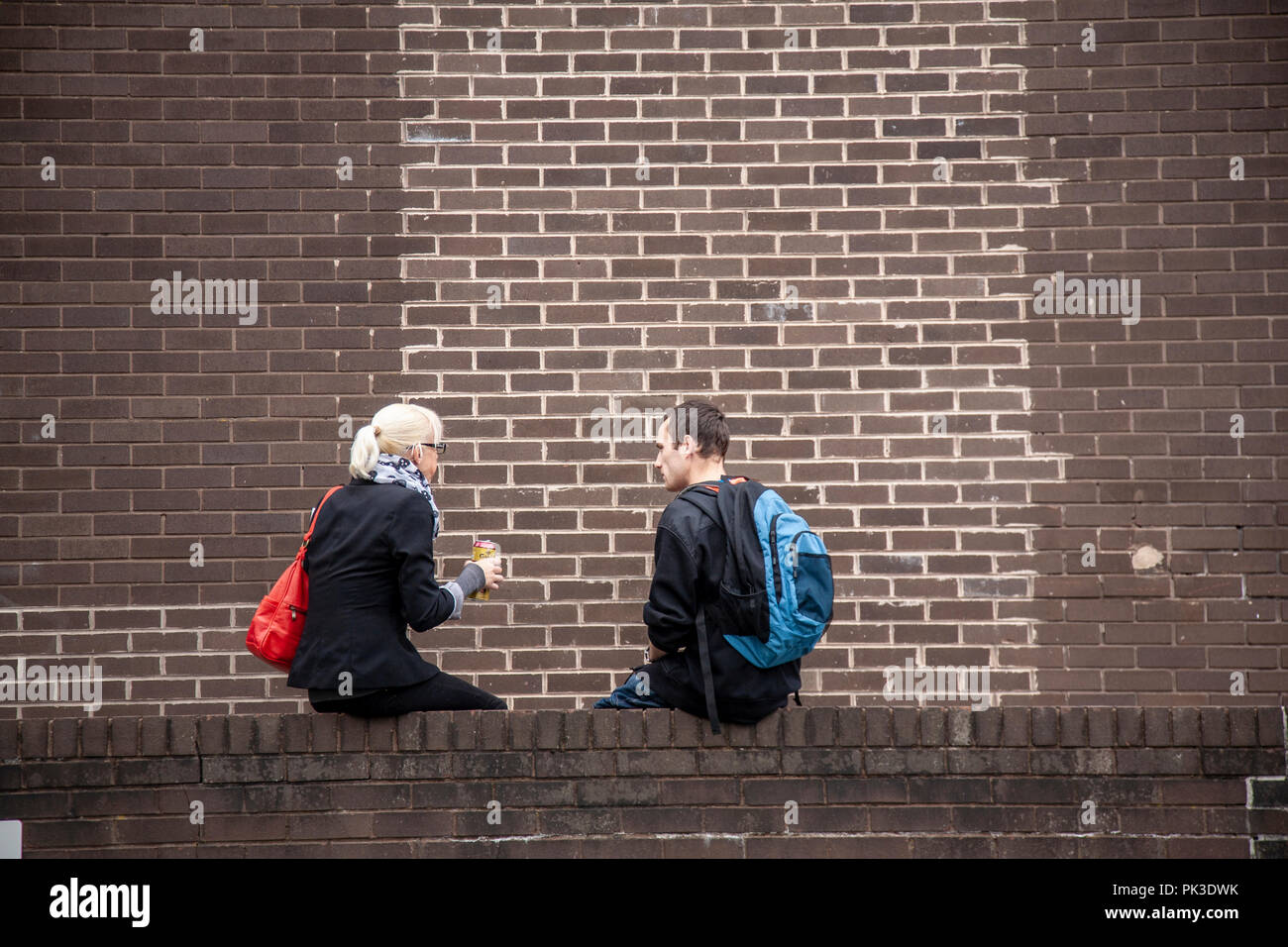 Mädchen und Jungen auf einer Wand in Huddersfield, West Yorkshire, England plaudernd Sitzen Stockfoto