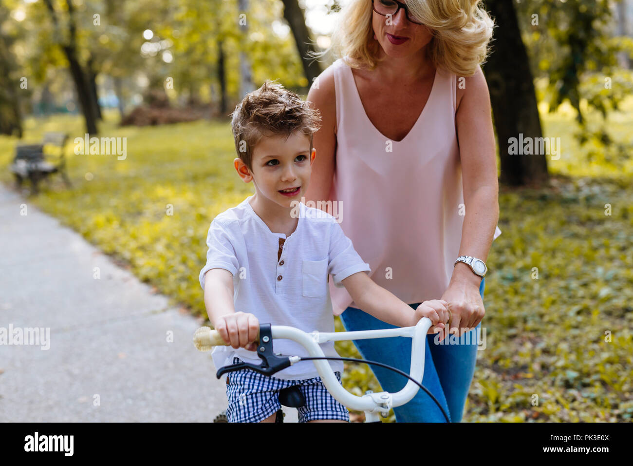 Kleiner Junge mit seiner Mutter lernen, ein Fahrrad im Park zu fahren Stockfoto