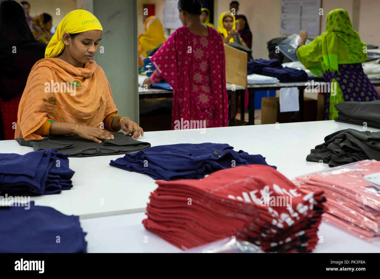 Eine weibliche Näherin Falten Kleidung auf der Linie von einer Textilfabrik, Bangladesch. Stockfoto