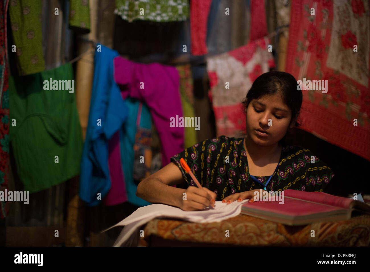 Eine Näherin Studium eine Krankenschwester bei ihr zu Hause in einem Slum von Dhaka, Bangladesch zu werden. Stockfoto