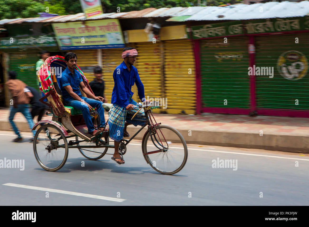 Ein Zyklus Rikscha befördern Passagiere in Dhaka, Bangladesh. Stockfoto