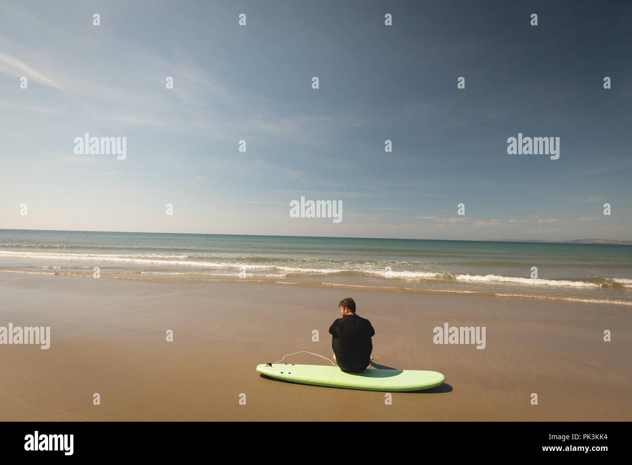 Surfer sitzen auf Surfboard am Strand Stockfoto