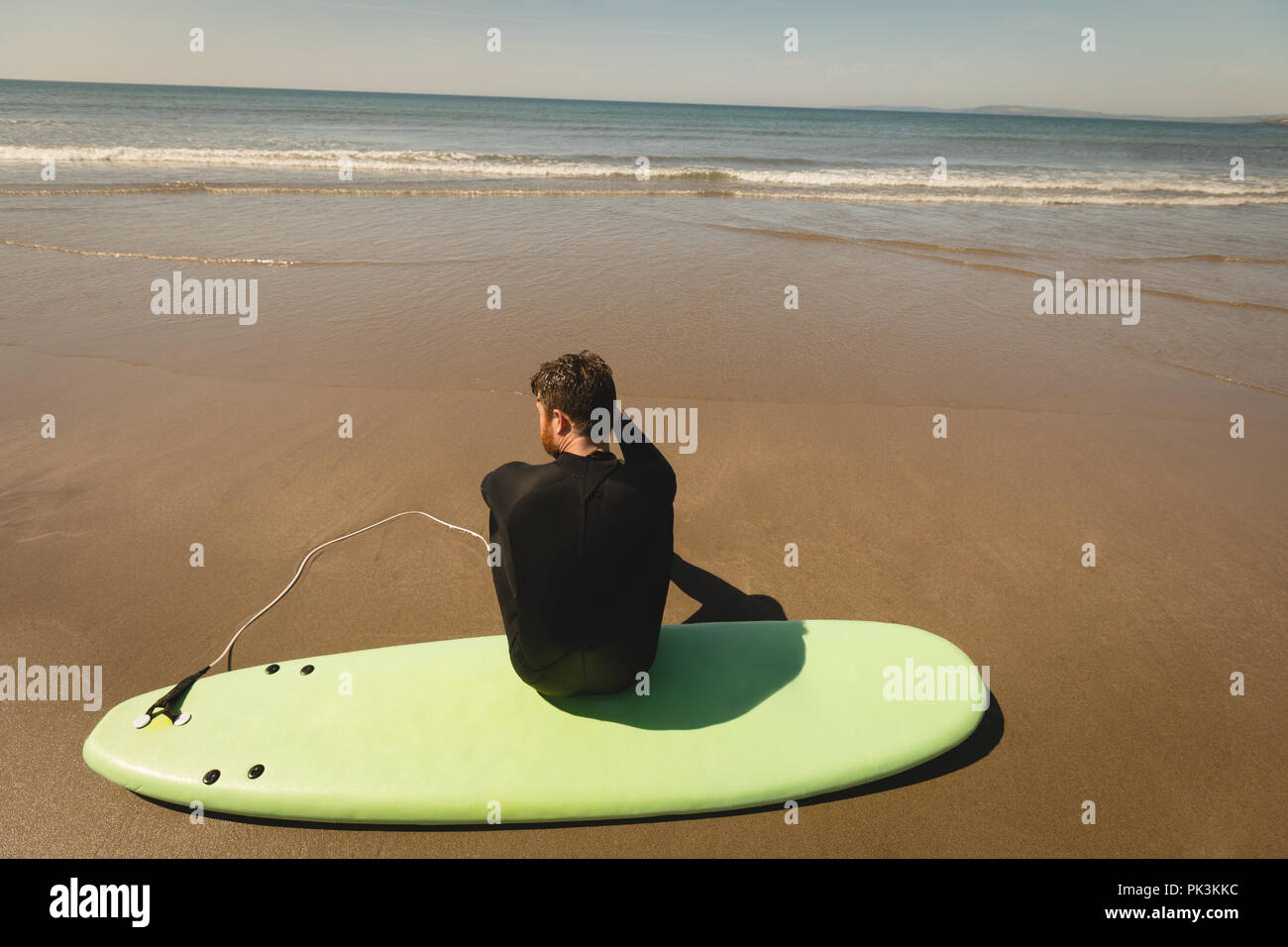Surfer sitzen auf Surfboard am Strand Stockfoto