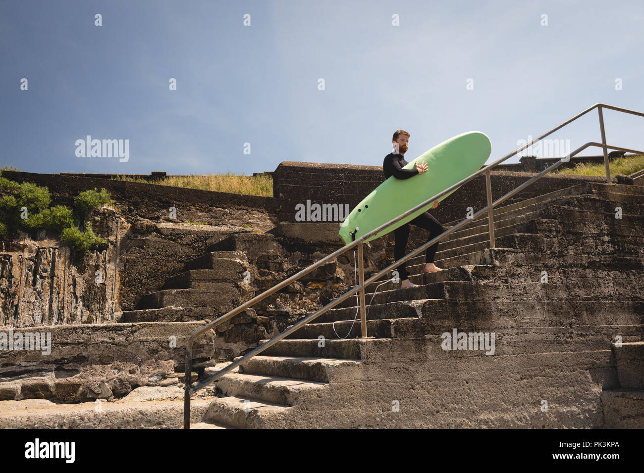 Surfer mit Surfbrett zu Fuß auf Treppe Stockfoto
