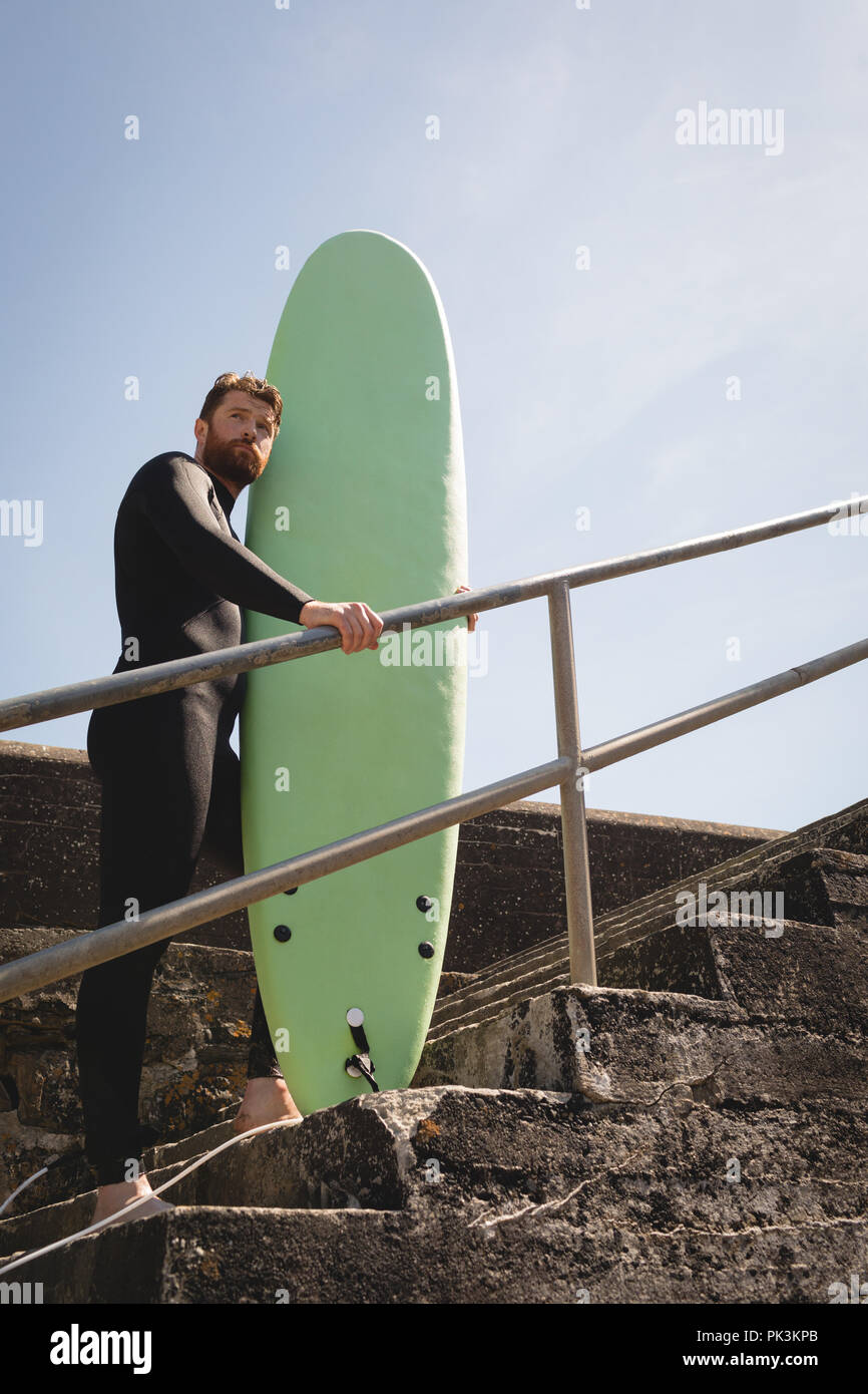 Surfer mit Surfbrett stehend auf Treppe Stockfoto