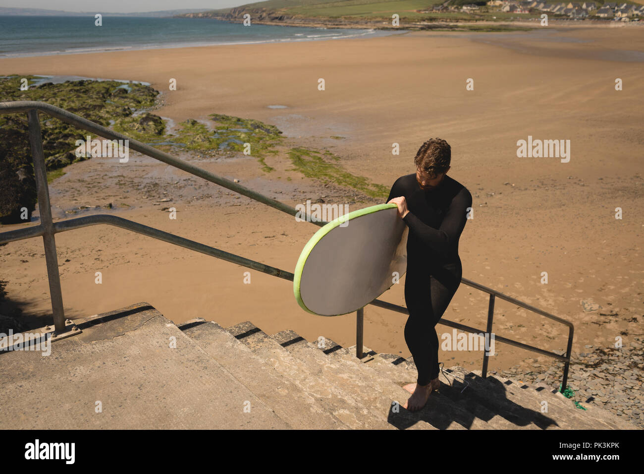 Surfer mit Surfbrett zu Fuß auf Treppe Stockfoto
