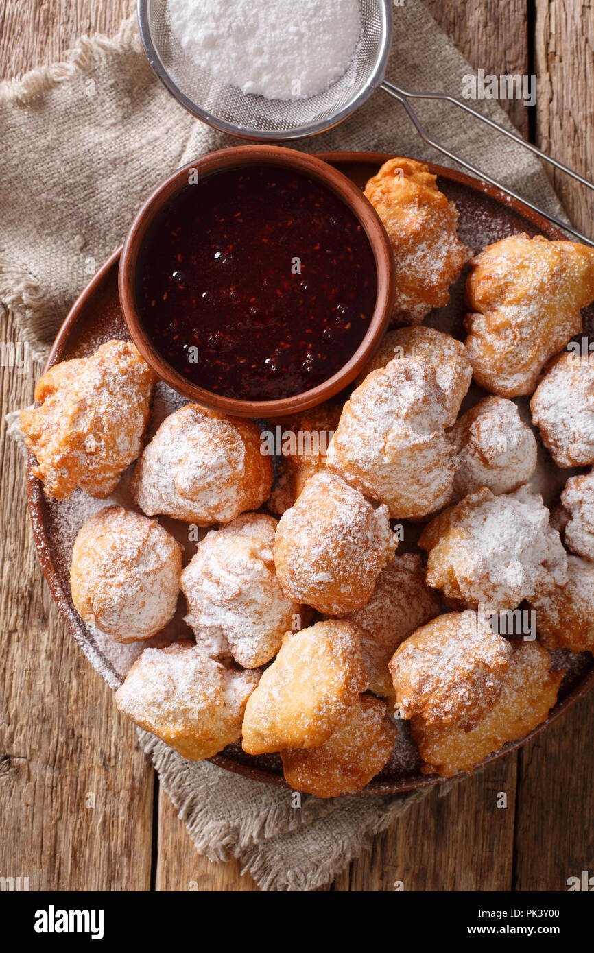 Leckere frittierte Krapfen mit himbeermarmelade und Puderzucker in der Nähe serviert werden - bis auf einen Teller auf den Tisch. Vertikal oben Ansicht von oben Stockfoto