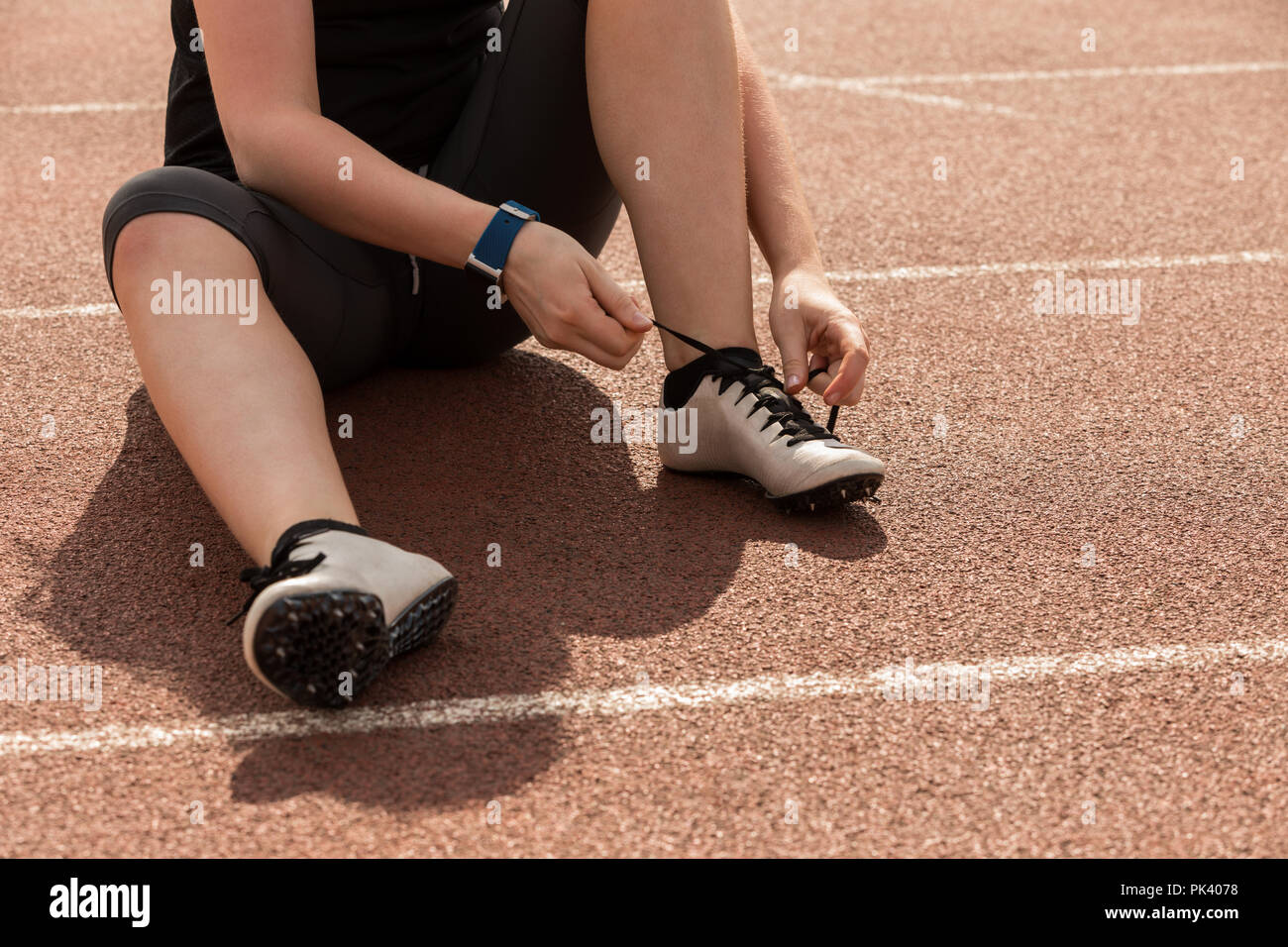 Weibliche athletische binden Schnürsenkel auf eine Laufstrecke Stockfoto