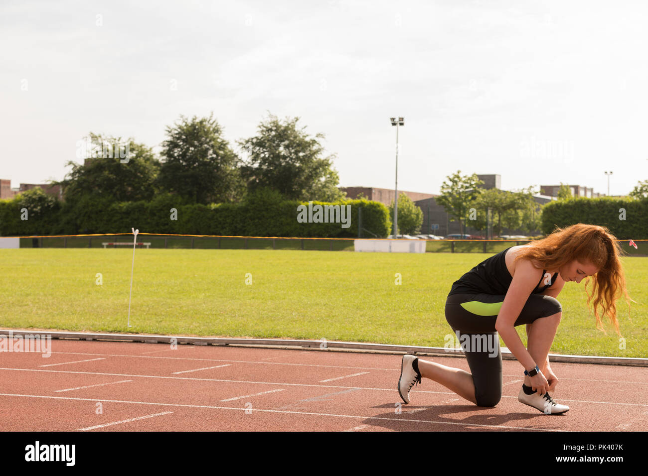 Weibliche athletische binden Schnürsenkel auf eine Laufstrecke Stockfoto