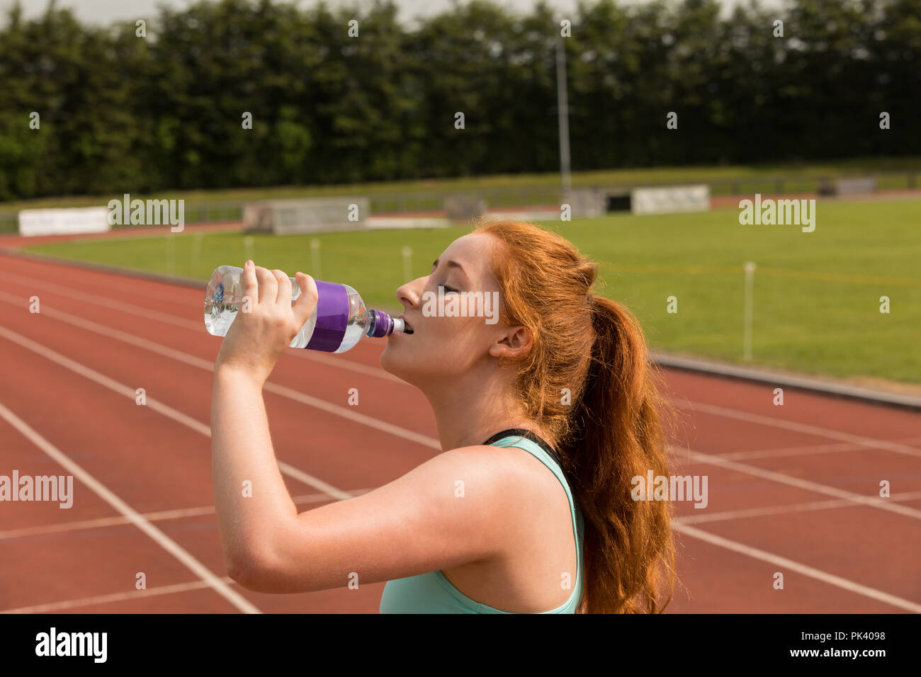 Weibliche athletische Trinkwasser auf der Laufstrecke Stockfoto