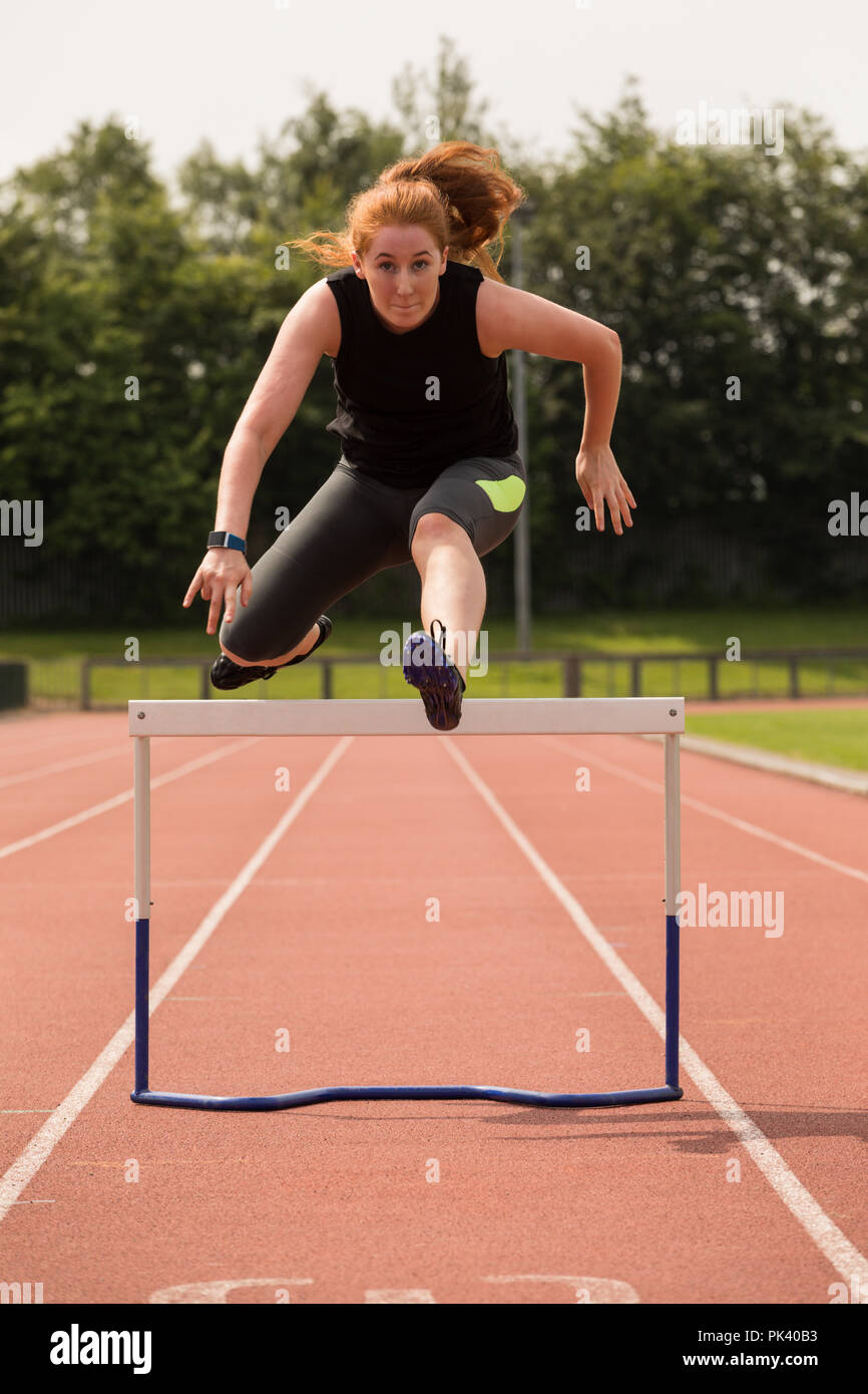 Weibliche athletische laufen über Hürde auf Sport Track Stockfoto