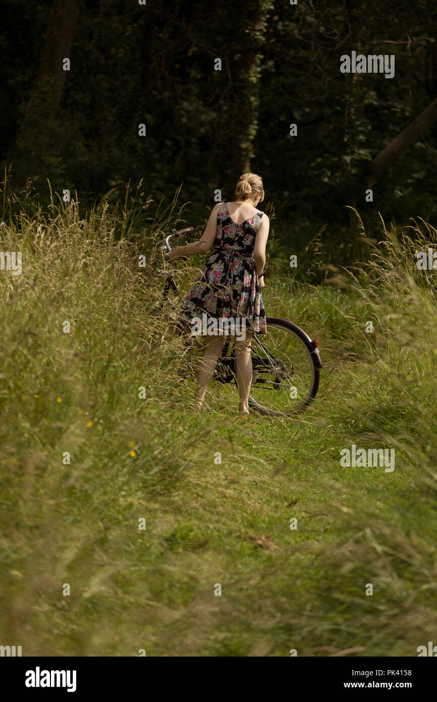 Frau, die mit dem Fahrrad in das Feld Stockfoto