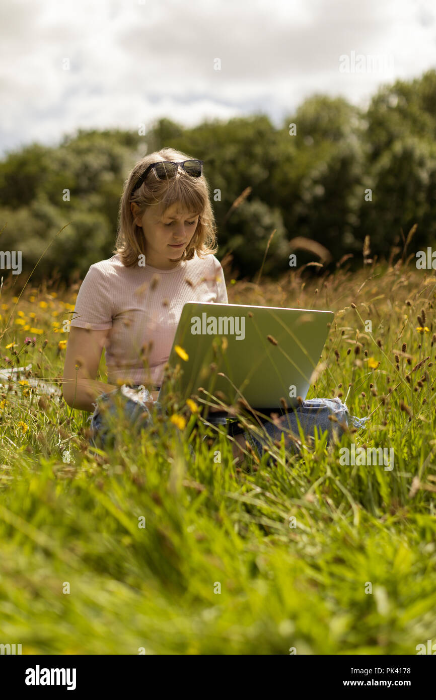 Frau mit Laptop im Feld Stockfoto