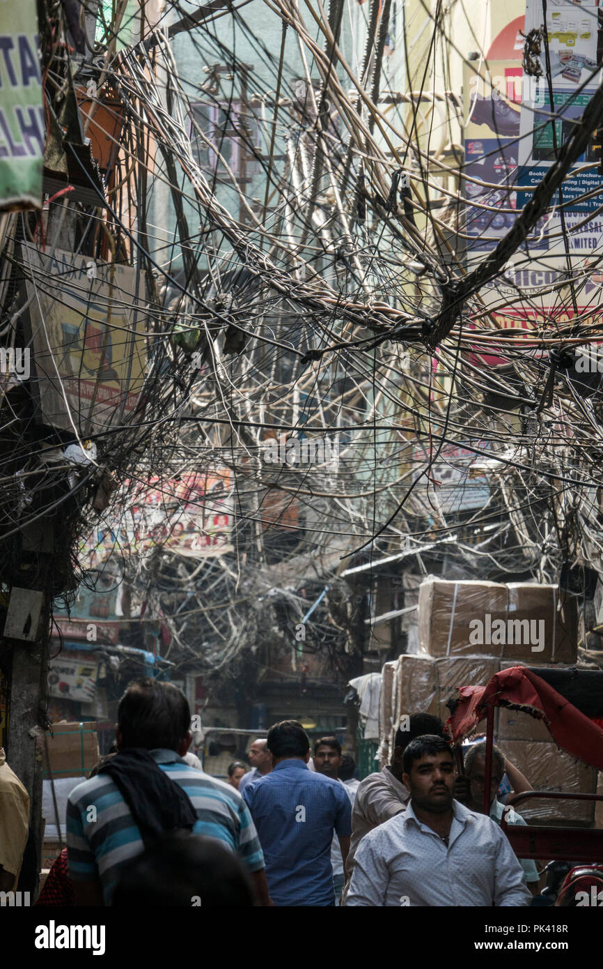 Fußgänger wandern in engen Straße mit großen's tangled Bird's Nest von Stromkabeln Overhead in Old Delhi, Neu-Delhi, Delhi, Indien Stockfoto