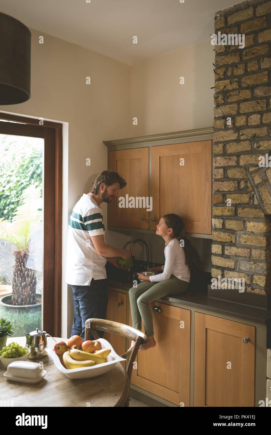 Vater und Tochter, die interagieren, während Gemüse waschen in der Küche Stockfoto