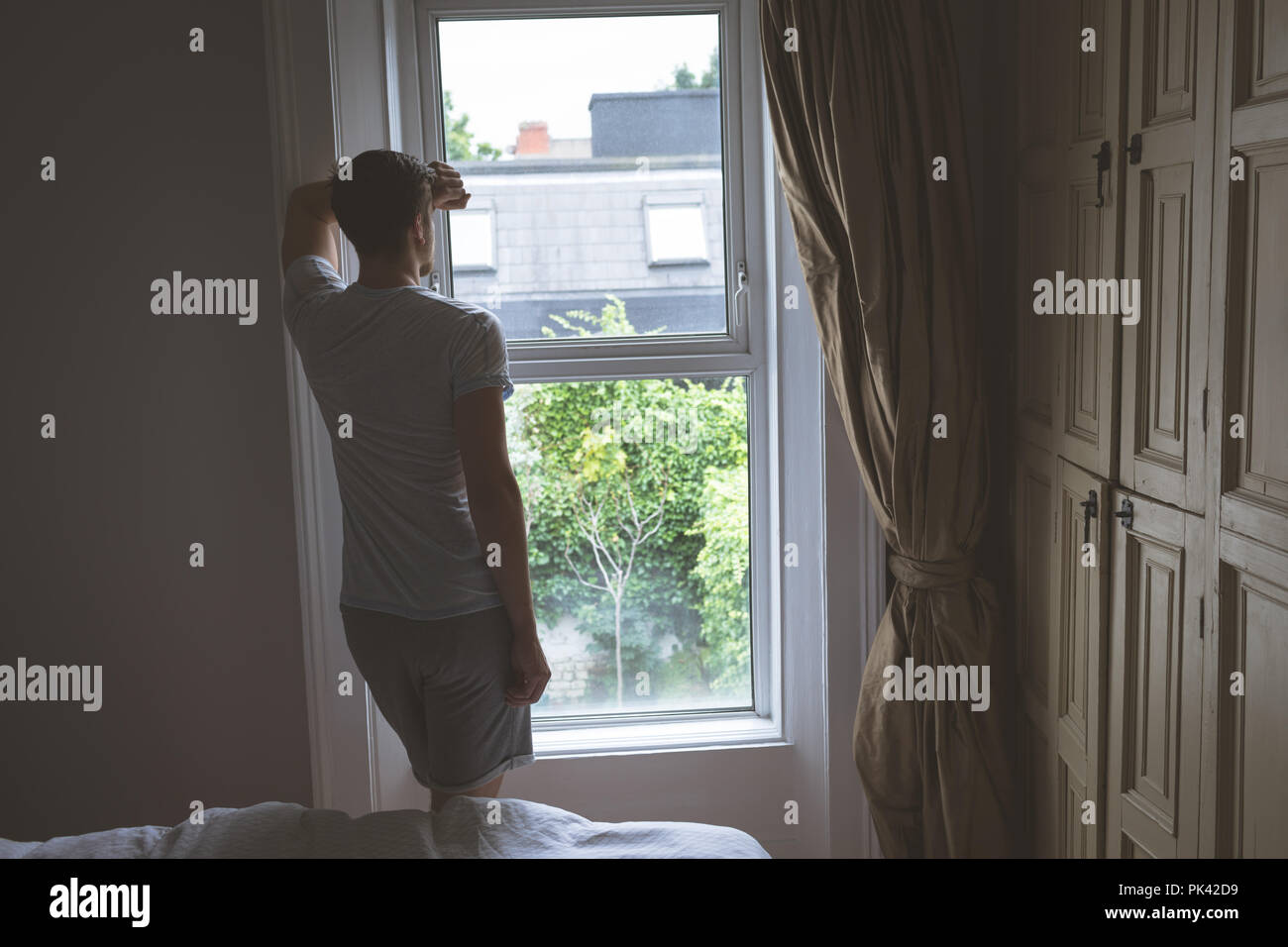 Mann auf der Suche durch Fenster zu Hause Stockfoto