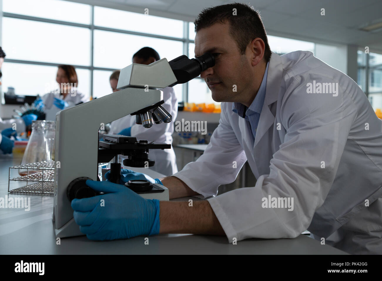 Männliche Wissenschaftler mittels Mikroskop Stockfoto